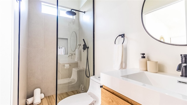 bathroom with vanity, hardwood / wood-style floors, toilet, and tiled shower