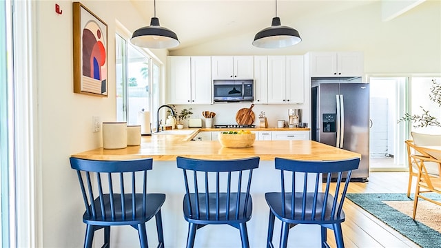 kitchen with wood counters, vaulted ceiling, sink, and stainless steel appliances