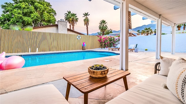 pool at dusk with a mountain view and a patio area