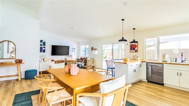 dining area with lofted ceiling, sink, and light wood-type flooring