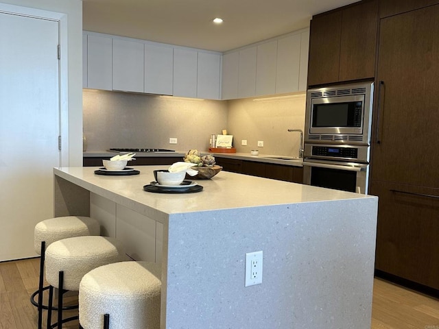 kitchen featuring a center island, light hardwood / wood-style floors, white cabinetry, appliances with stainless steel finishes, and sink