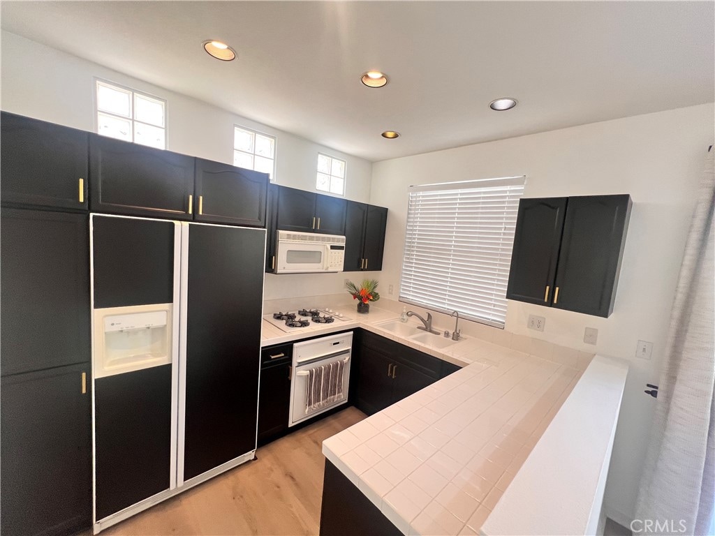 kitchen featuring white appliances, kitchen peninsula, sink, and light wood-type flooring