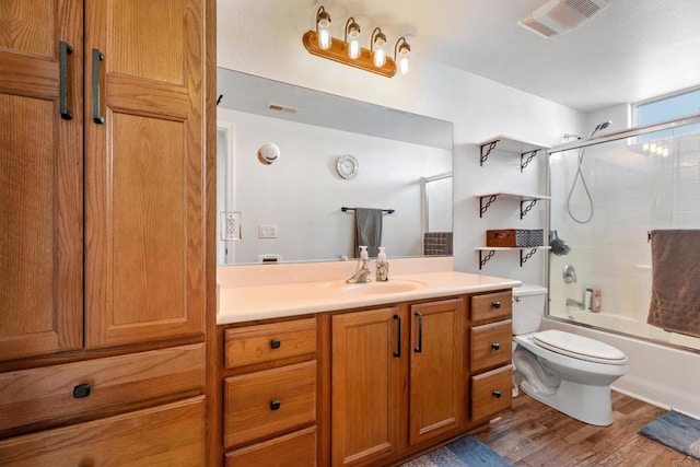 full bathroom with vanity, toilet, wood-type flooring, and enclosed tub / shower combo