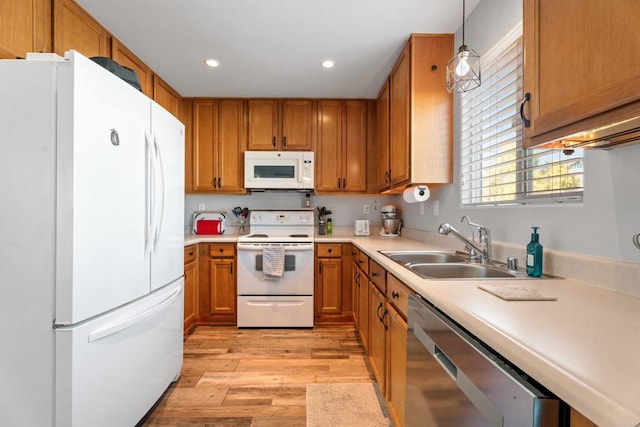 kitchen featuring pendant lighting, light wood-type flooring, sink, and white appliances