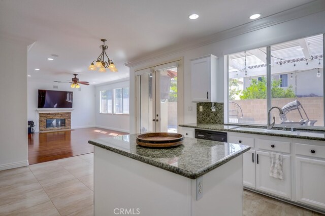 kitchen with white cabinetry, sink, decorative light fixtures, and a kitchen island