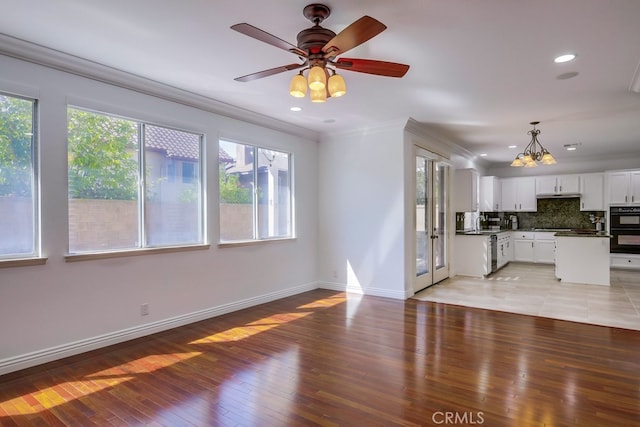 unfurnished living room with ceiling fan, crown molding, a healthy amount of sunlight, and light wood-type flooring