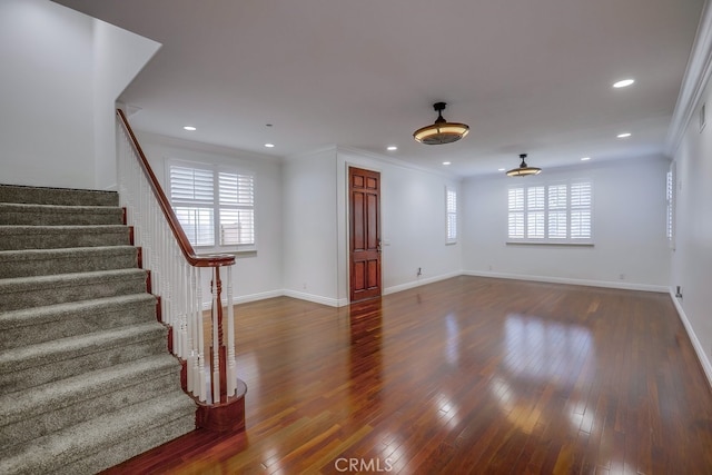 unfurnished living room featuring ornamental molding and dark hardwood / wood-style flooring