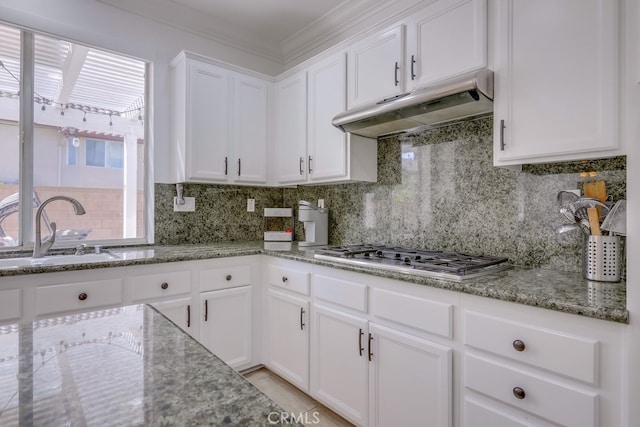 kitchen with decorative backsplash, stainless steel gas stovetop, light stone countertops, and white cabinets