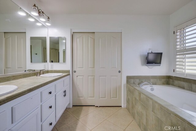 bathroom featuring tile patterned flooring, vanity, and tiled bath