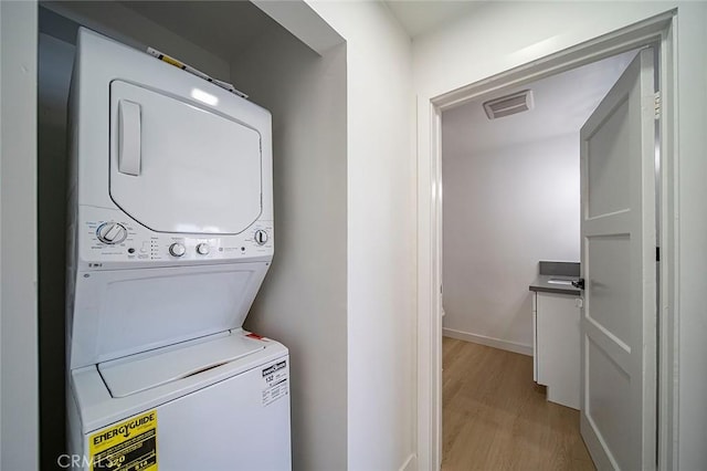 laundry area featuring light hardwood / wood-style floors and stacked washer and dryer