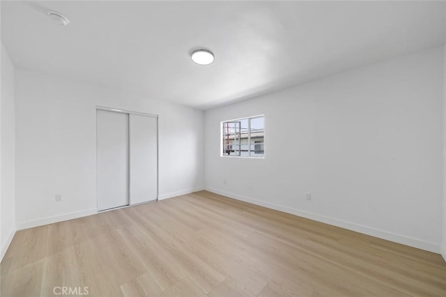 unfurnished bedroom with light wood-type flooring and a closet