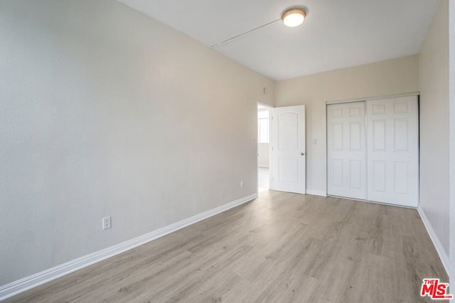 unfurnished bedroom featuring a closet and light wood-type flooring