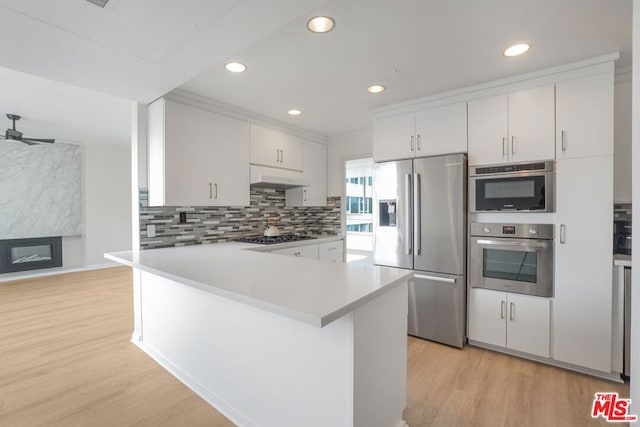 kitchen with white cabinetry, ceiling fan, a premium fireplace, appliances with stainless steel finishes, and light wood-type flooring