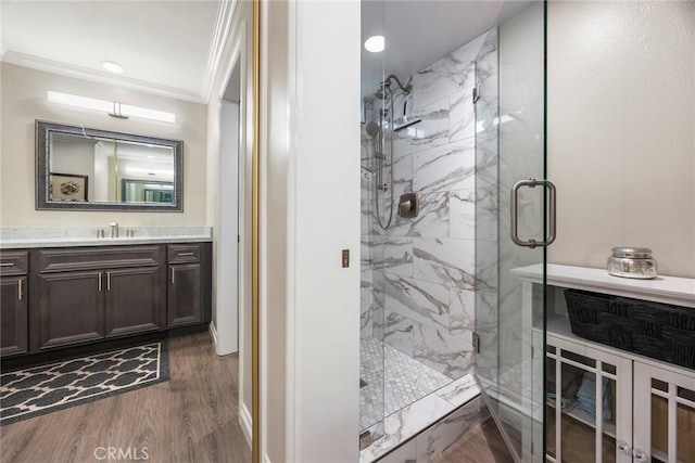 bathroom with baseboards, a marble finish shower, ornamental molding, wood finished floors, and vanity
