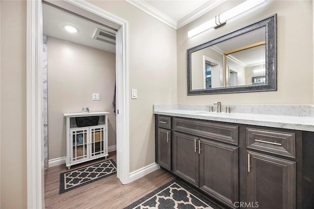 bathroom with visible vents, baseboards, ornamental molding, wood finished floors, and vanity