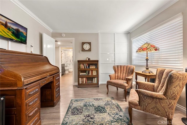 sitting room with crown molding, baseboards, and light wood-style floors