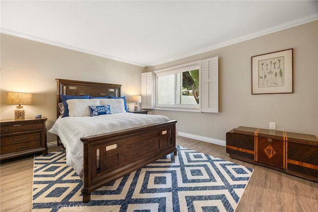 bedroom featuring baseboards, ornamental molding, and light wood-style floors