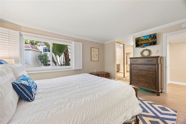 bedroom with baseboards, light wood-type flooring, ensuite bath, and crown molding