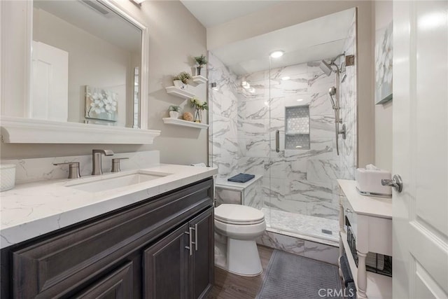 full bath with toilet, a marble finish shower, wood finished floors, and vanity