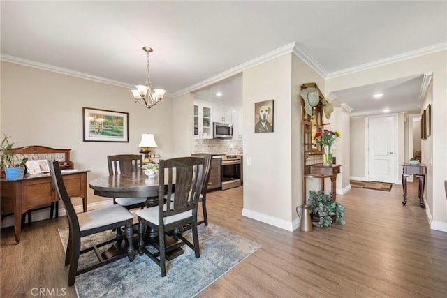 dining room featuring wood finished floors, a chandelier, crown molding, and baseboards
