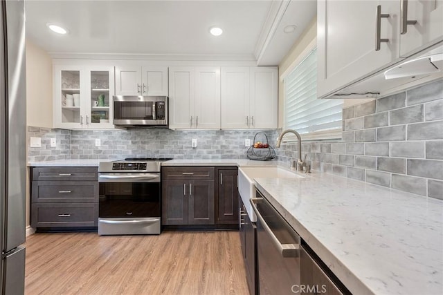 kitchen with light stone countertops, a sink, white cabinets, and appliances with stainless steel finishes