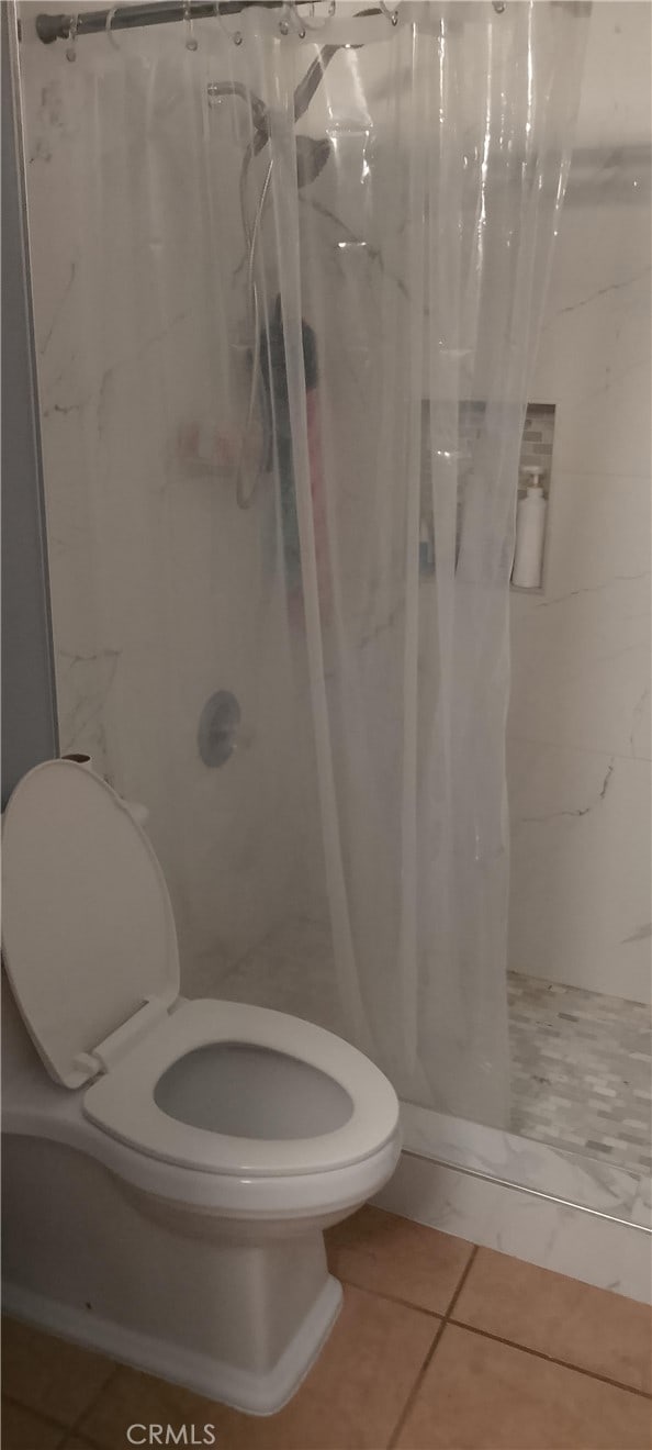 bathroom with tile patterned floors, a shower with curtain, and toilet