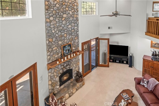 living room with ceiling fan, french doors, a towering ceiling, light colored carpet, and a fireplace