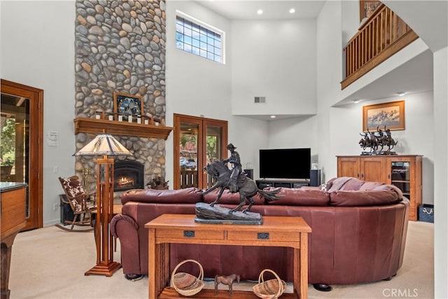 carpeted living room with a fireplace and a towering ceiling