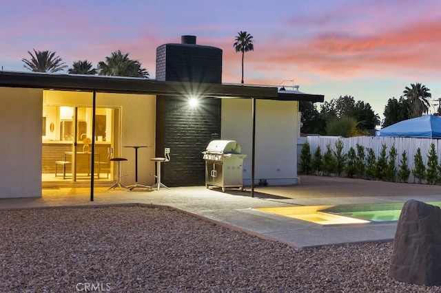 rear view of property with a patio, a chimney, fence, and stucco siding