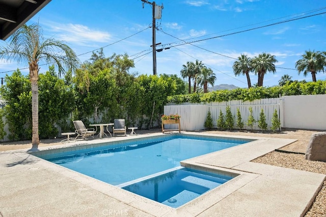 view of swimming pool featuring a patio, a fenced backyard, and a pool with connected hot tub