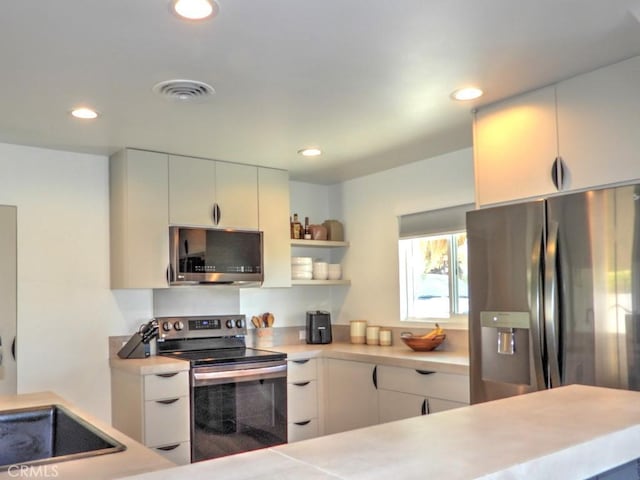 kitchen with appliances with stainless steel finishes, light countertops, visible vents, and open shelves