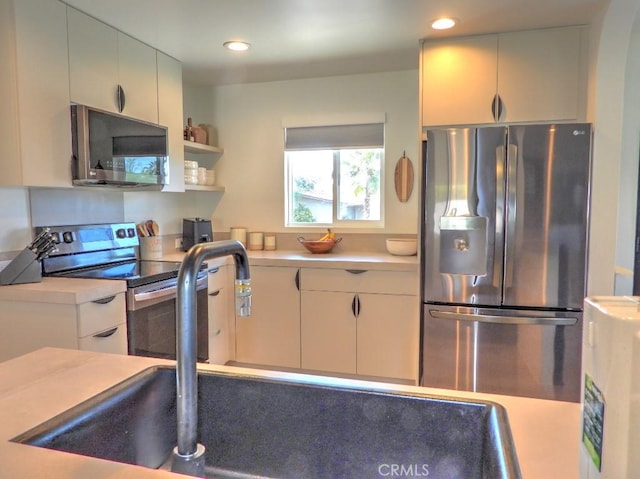 kitchen featuring stainless steel appliances, light countertops, open shelves, a sink, and recessed lighting