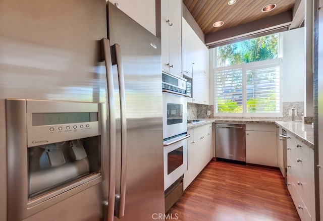 kitchen with appliances with stainless steel finishes, tasteful backsplash, wood ceiling, hardwood / wood-style floors, and white cabinetry