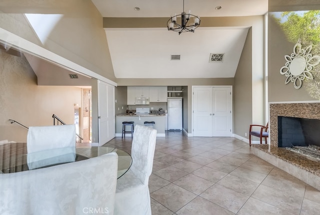 unfurnished living room with light tile patterned floors, high vaulted ceiling, an inviting chandelier, and a premium fireplace