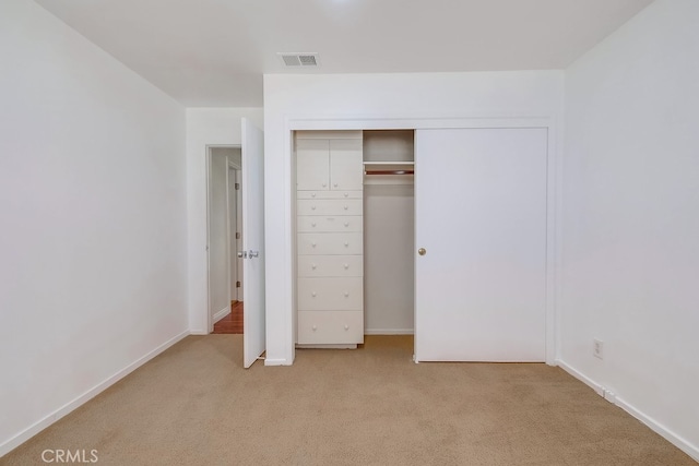 unfurnished bedroom with light colored carpet and a closet