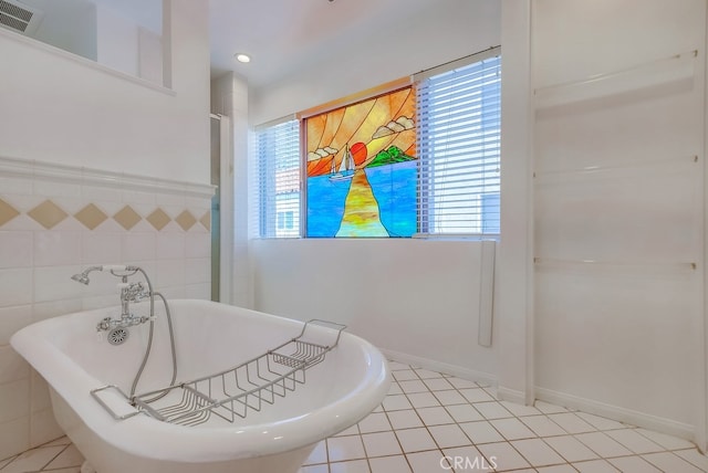 bathroom with tile patterned flooring, a bath, and tile walls