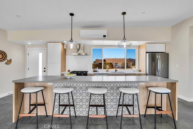 kitchen featuring stainless steel fridge, wall chimney exhaust hood, decorative light fixtures, and white cabinets