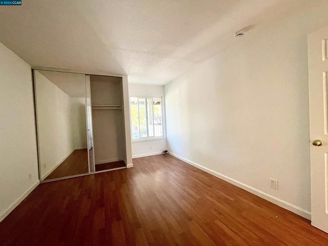 unfurnished bedroom featuring dark hardwood / wood-style flooring and a closet