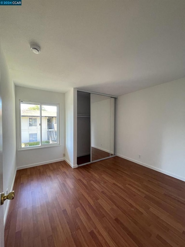 unfurnished bedroom with dark hardwood / wood-style floors and a closet