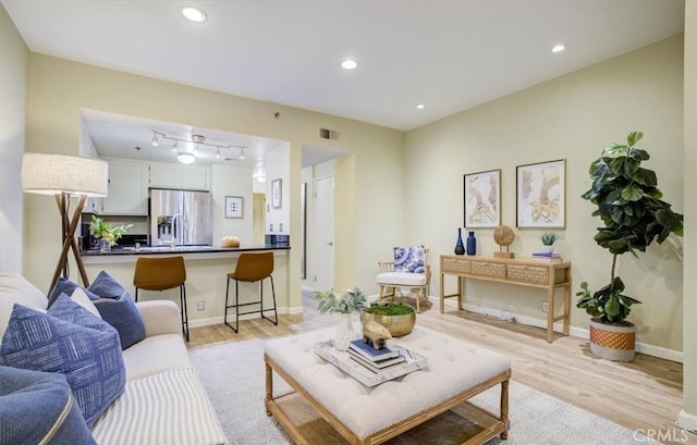 living room with rail lighting and light hardwood / wood-style floors