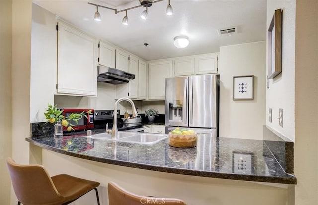 kitchen with stainless steel appliances, under cabinet range hood, a sink, visible vents, and a peninsula