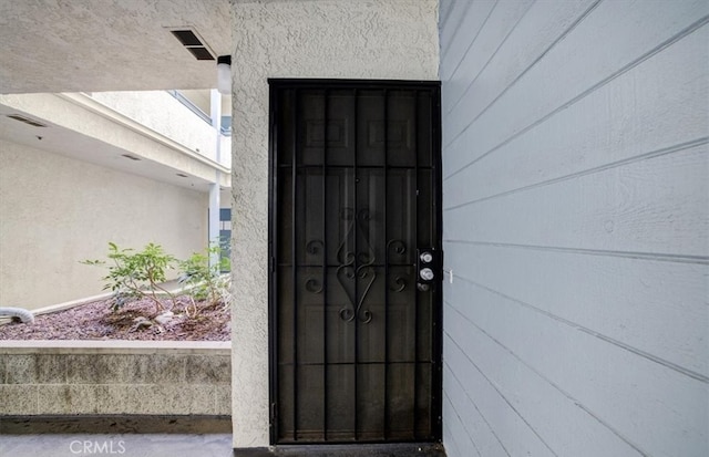 entrance to property featuring visible vents and stucco siding