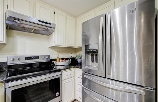 kitchen featuring under cabinet range hood, white cabinets, dark stone countertops, and appliances with stainless steel finishes