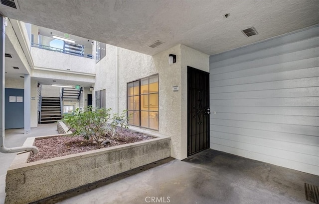 view of exterior entry with stucco siding and visible vents