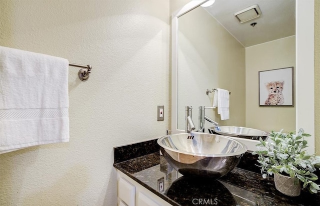 bathroom featuring a textured wall and vanity