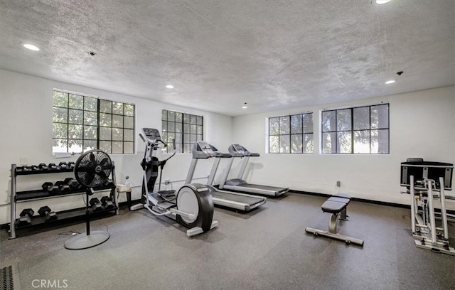 exercise room with recessed lighting, a healthy amount of sunlight, and a textured ceiling