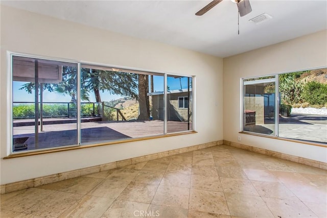 empty room featuring ceiling fan and a wealth of natural light