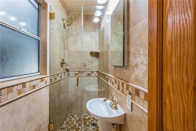 bathroom with a shower with door, tile walls, and sink