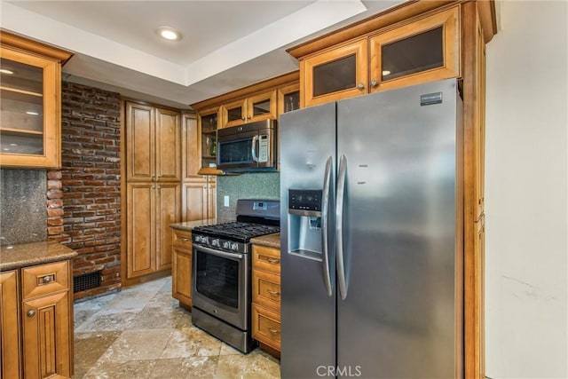 kitchen with backsplash, appliances with stainless steel finishes, and dark stone counters