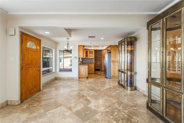 kitchen featuring stainless steel refrigerator, hanging light fixtures, a notable chandelier, and sink